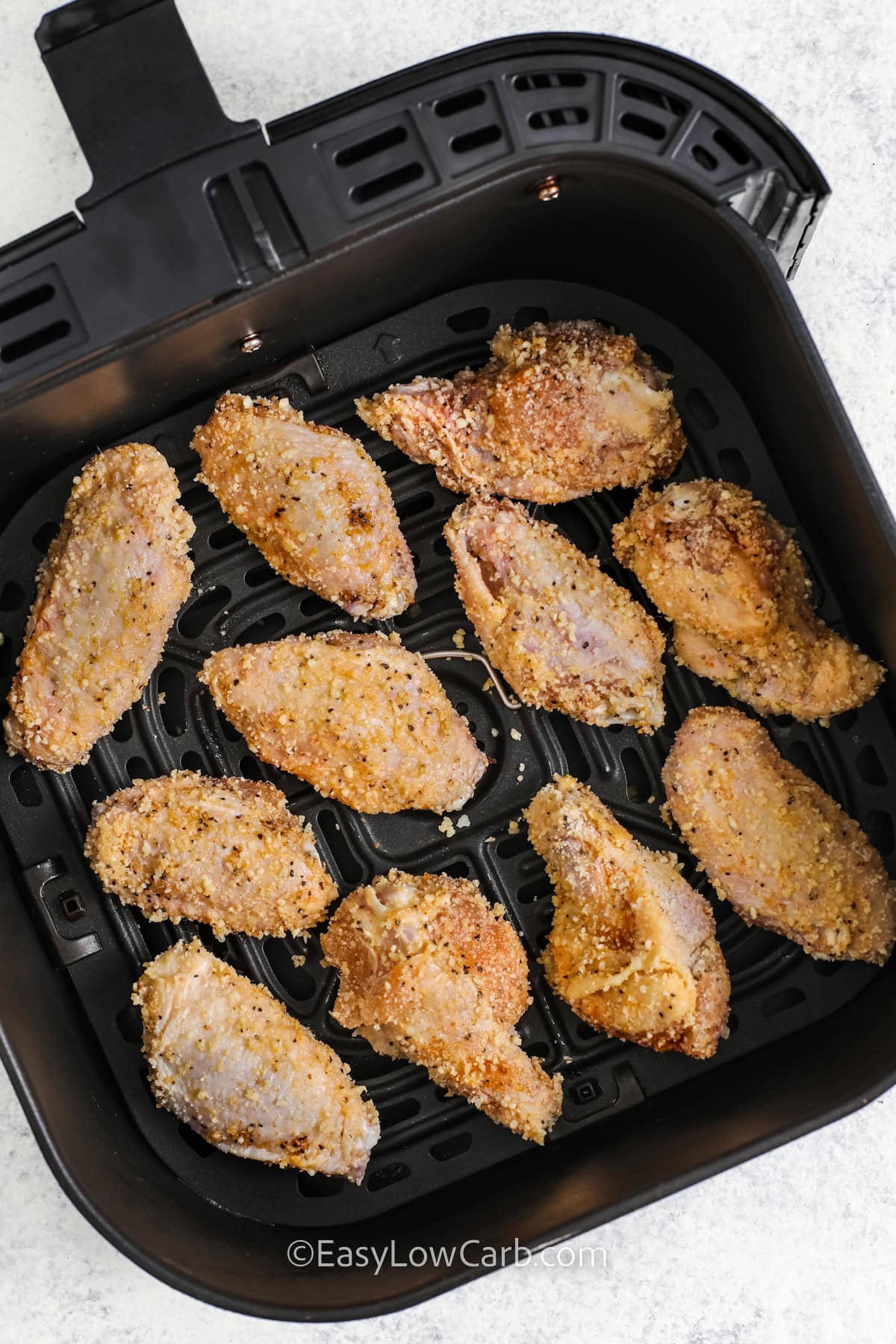 uncooked garlic parmesan chicken wings in an air fryer tray