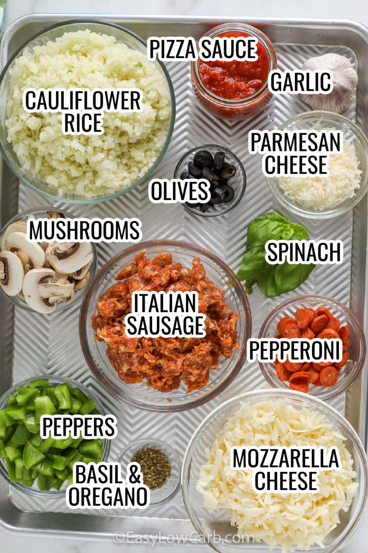 ingredients assembled to make pizza bowls, including cauliflower rice, pizza sauce, garlic, mushrooms, italian sausage, pepperoni, peppers, parmesan and mozzarella cheese