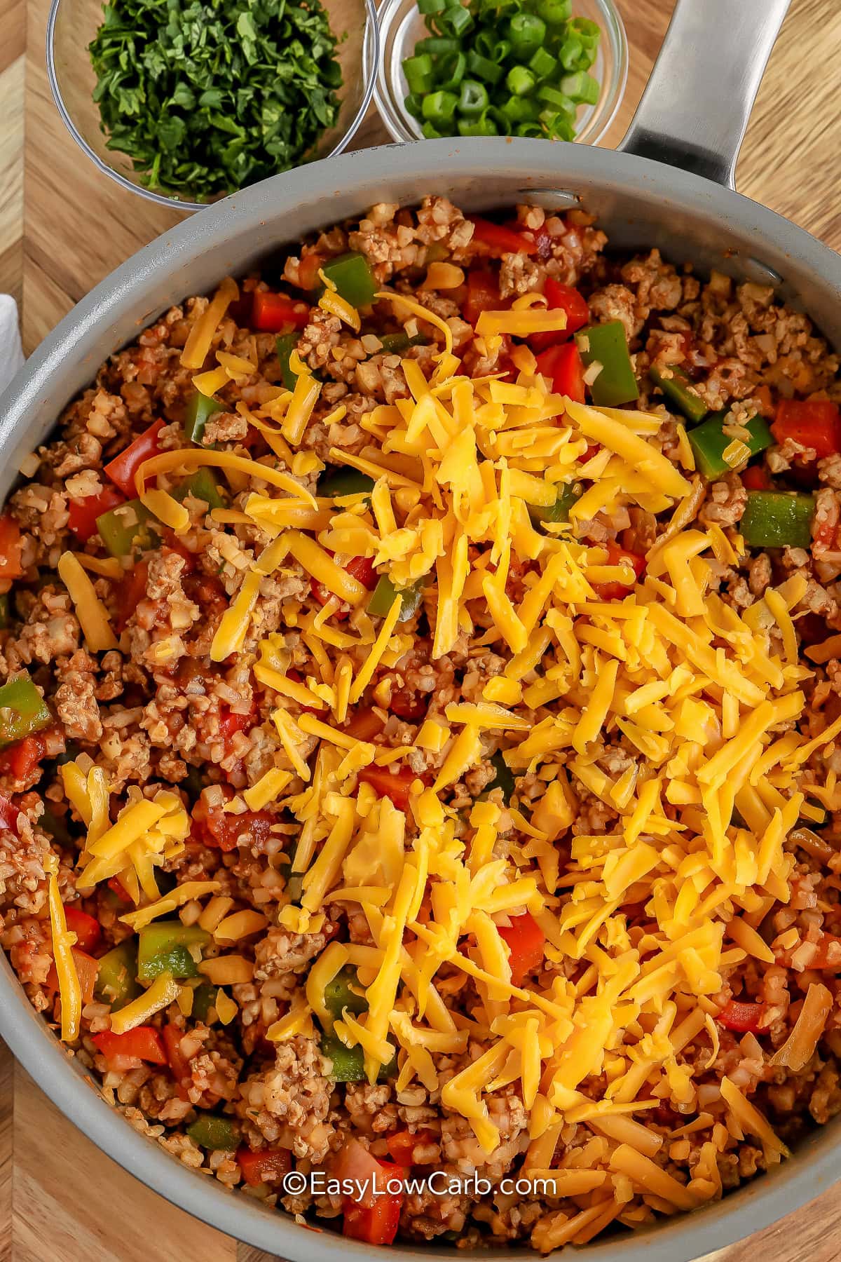adding cheese on top of Cheesy Taco Skillet