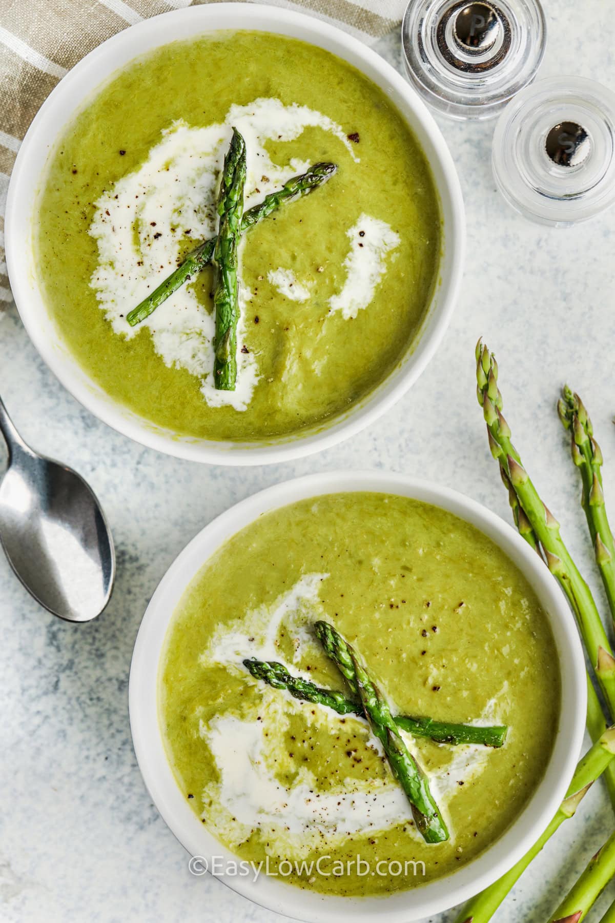 bowls of Creamy Asparagus Soup with cream , asparagus and pepper on top