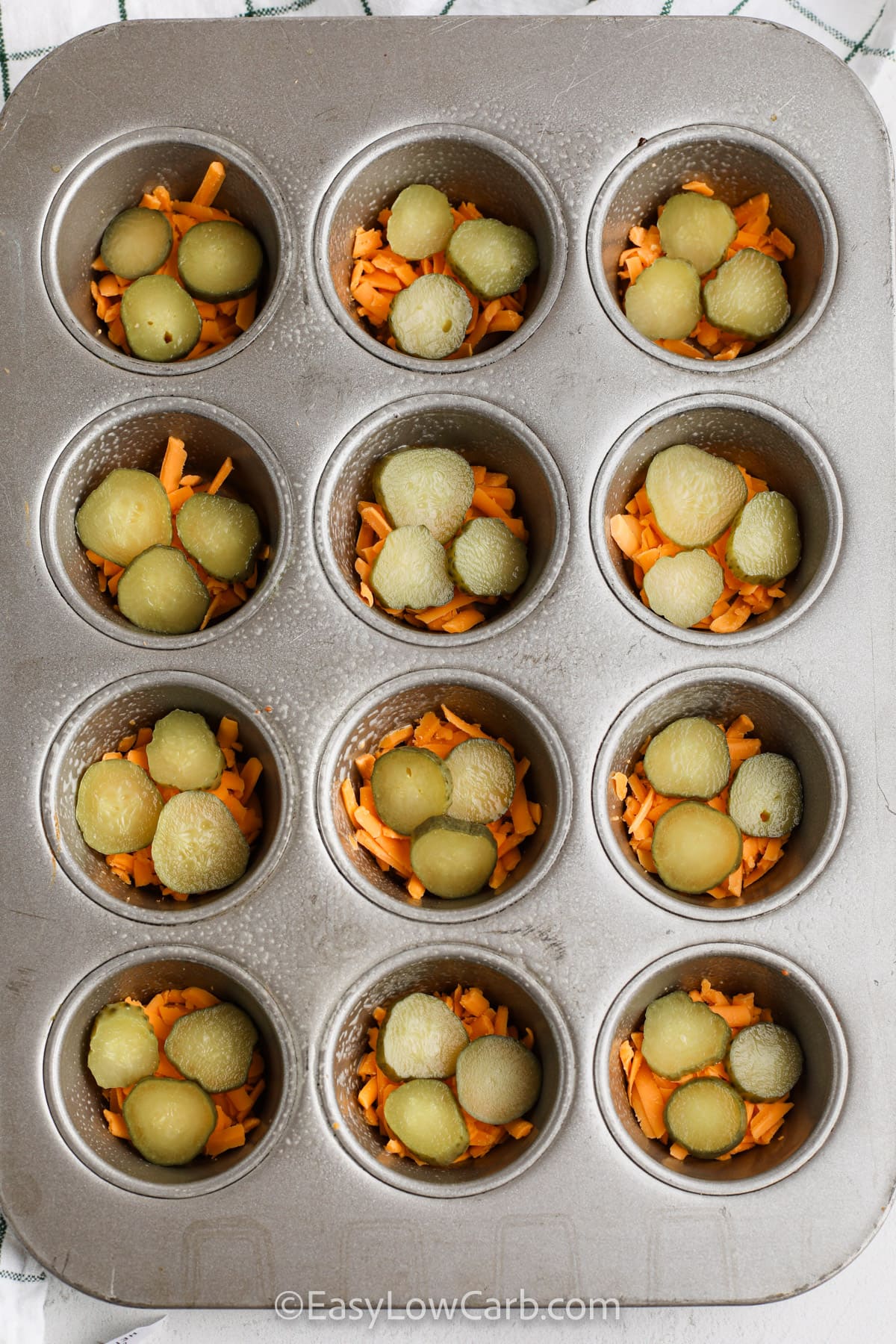 cheese and pickles in a muffin tin to make pickle chips