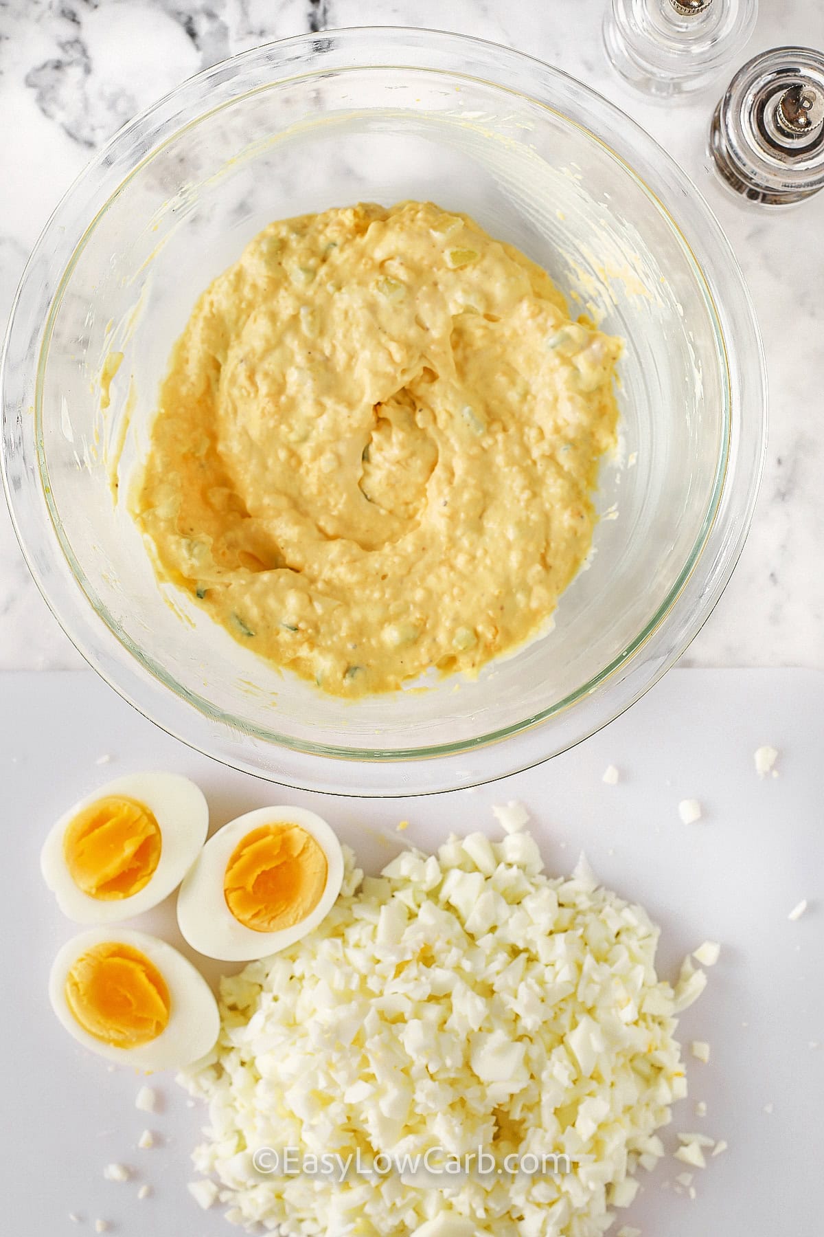 mixed cooked egg yolks with seasonings in a bowl with cut up egg whites to make Curried Egg Salad