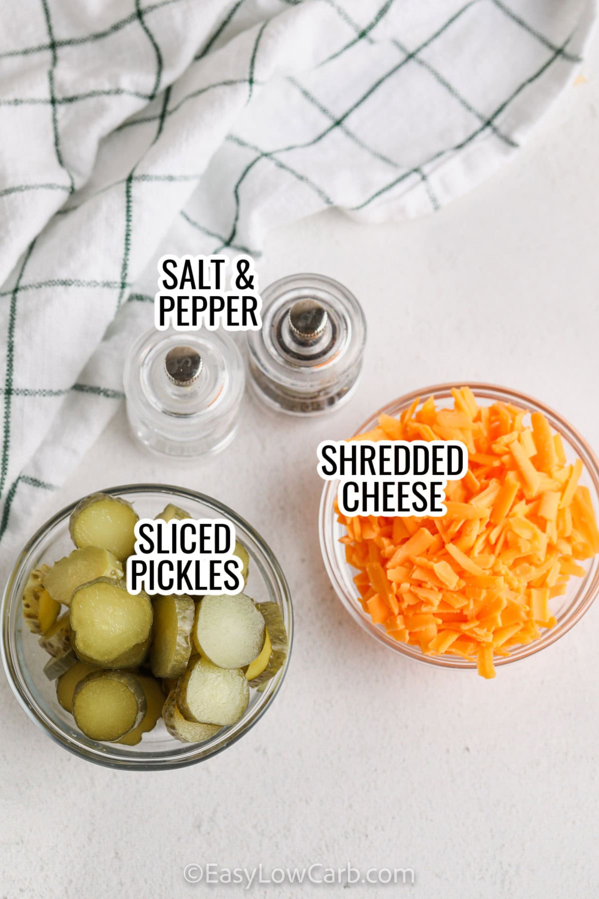 ingredients assembled to make crispy Pickle Chips, including pickles, salt and pepper, and shredded cheese