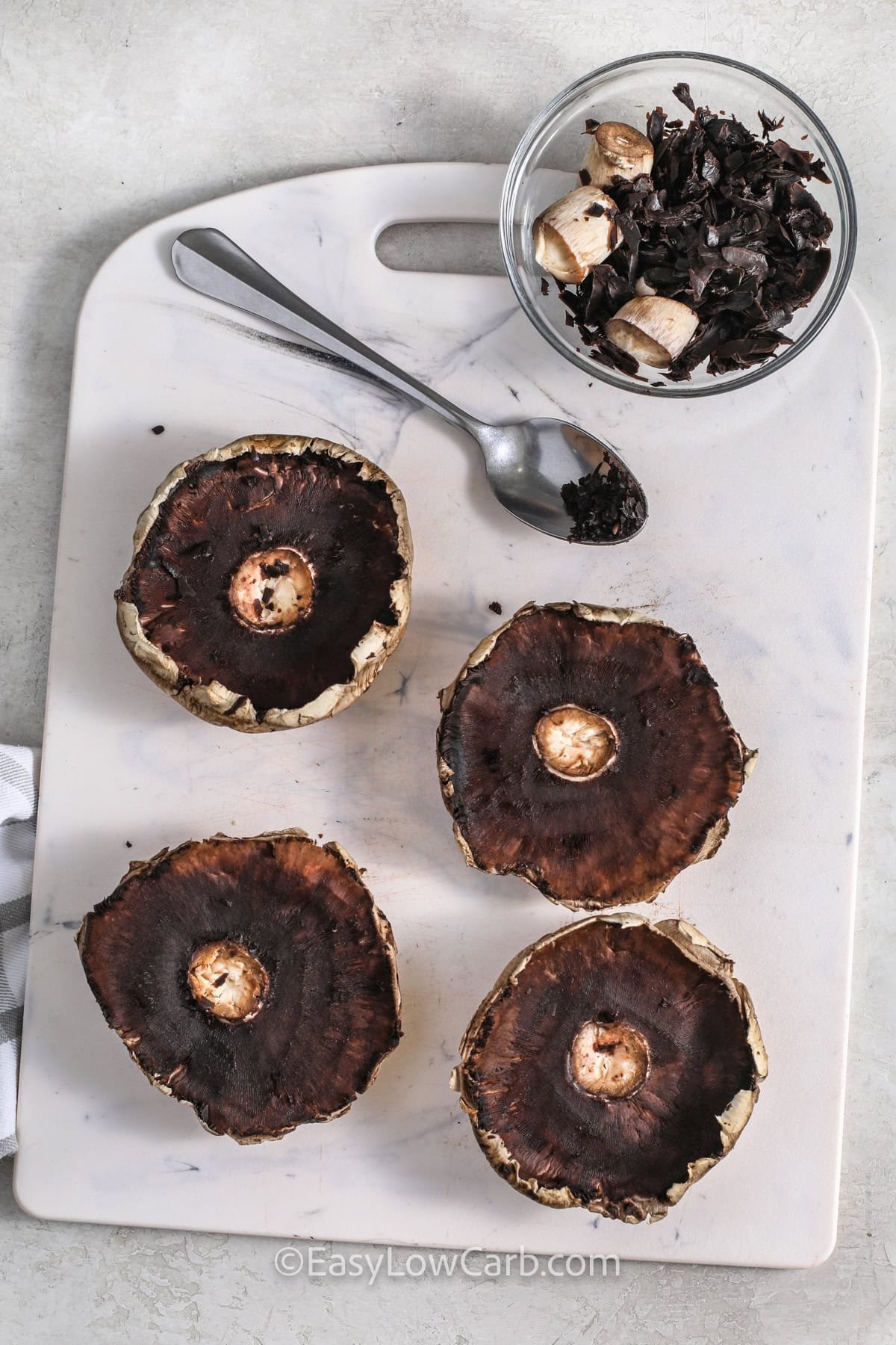 scooping out mushrooms to make adding cheese to Lasagna Stuffed Mushrooms