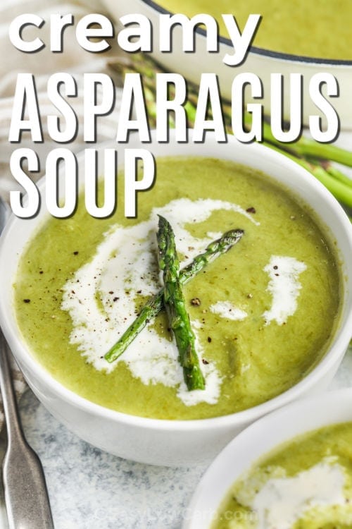 Creamy Asparagus Soup in a bowl with cream and asparagus on top with writing
