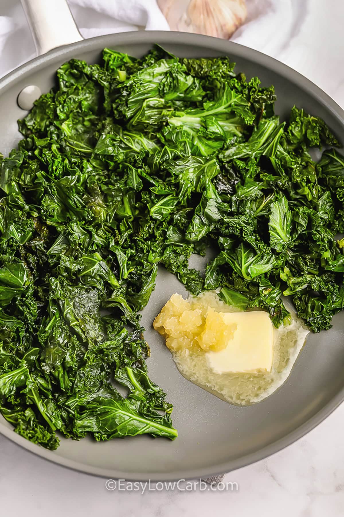 adding garlic and butter to kale in pan to make Sautéed Kale