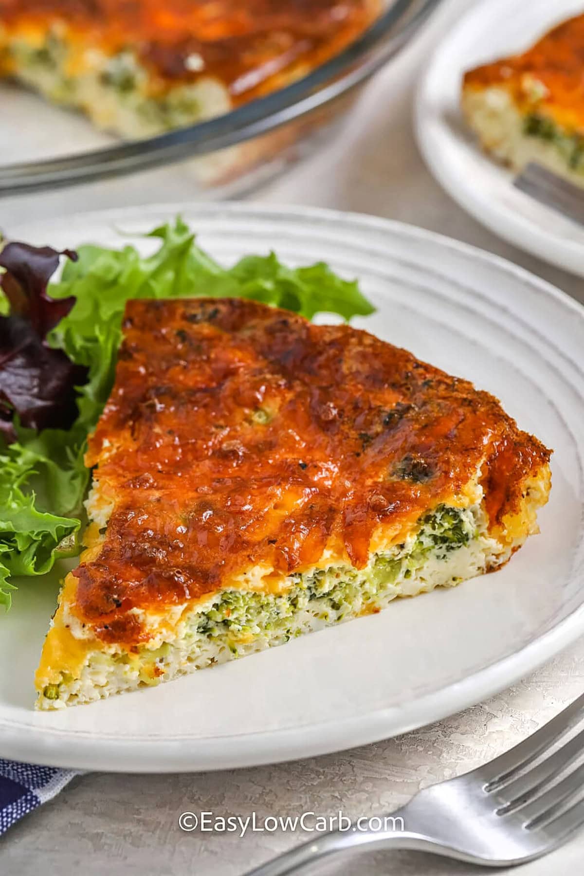 With fresh broccoli, savory cheddar cheese, and a creamy egg filling, this easy quiche is sure to be a hit. No crust means fewer carbs and less work—just sauté the broccoli, mix the ingredients, and let the oven do the rest. It’s a great make-ahead dish for meal prep or a last-minute brunch that comes together in no time. Serve it warm or cold for a satisfying meal that’s packed with cheesy goodness. #easylowcarb slice of Broccoli Cheese Quiche on a plate