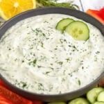 Homemade Tzatziki in a bowl with vegetables around the bowl