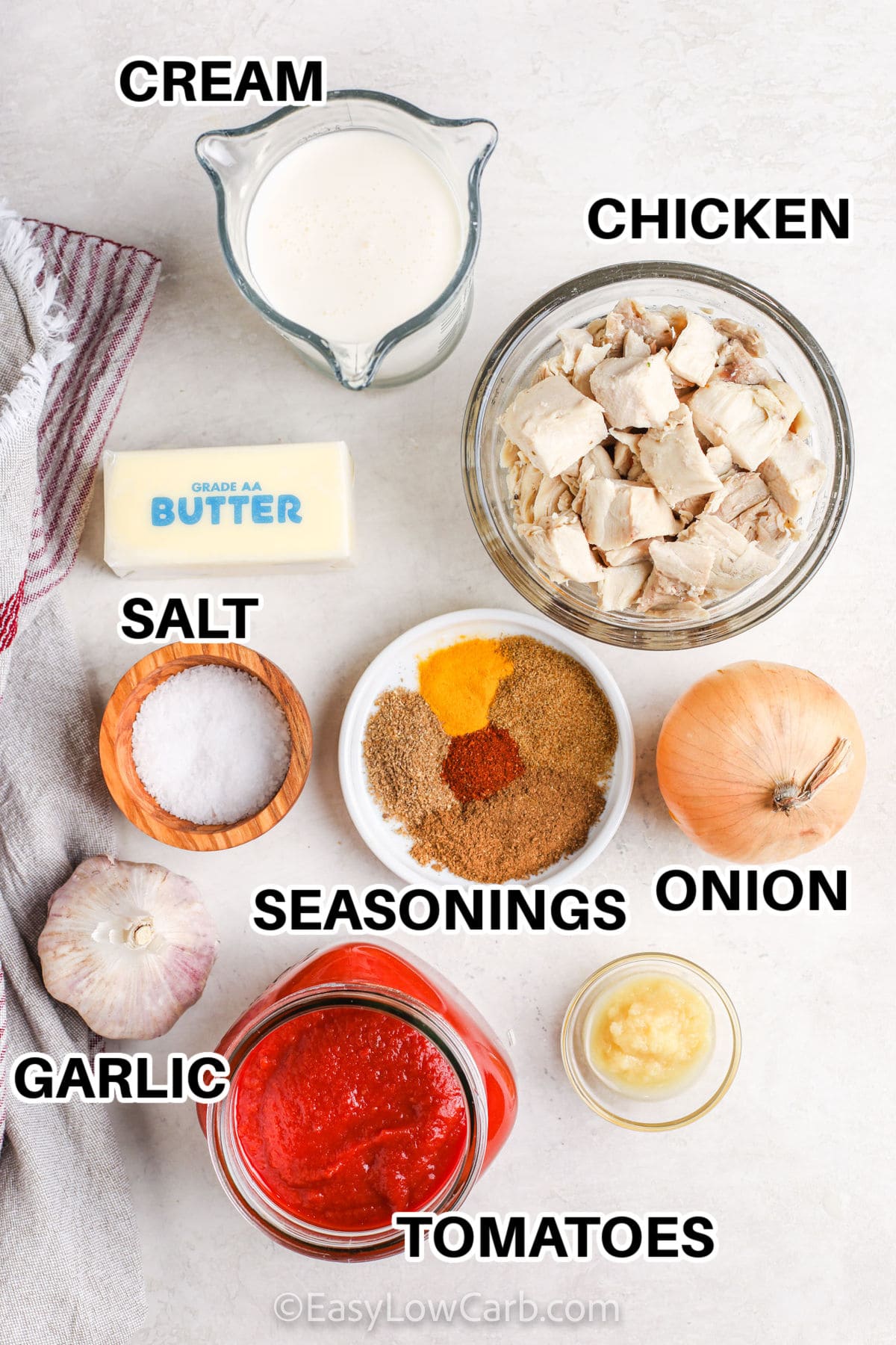 ingredients assembled to make easy butter chicken, including chicken, cream, garlic, tomatoes, onion, salt, butter, and seasoning