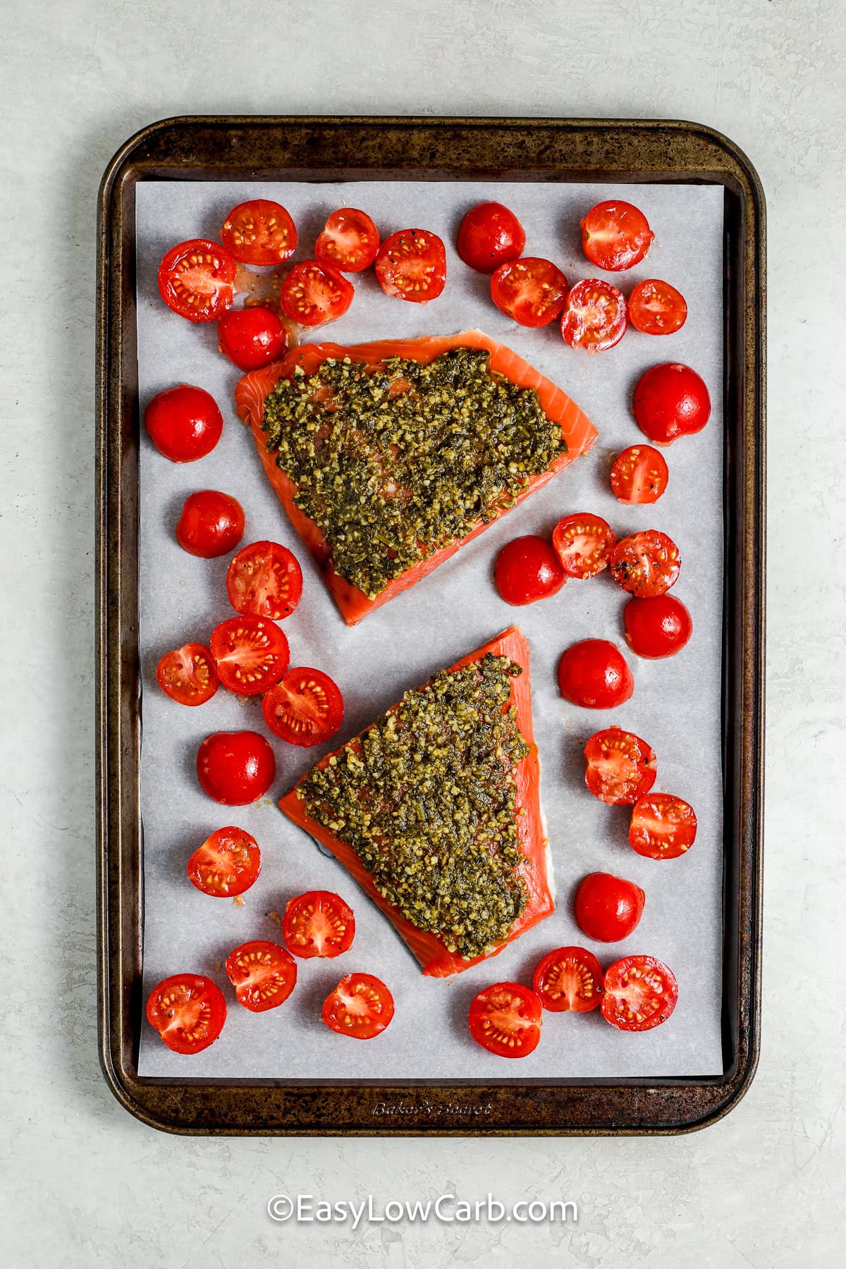 adding ingredients to sheet pan to make Pesto Salmon Recipe