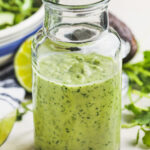 Avocado Lime Dressing in a jar and on a spoon with salad in a bowl