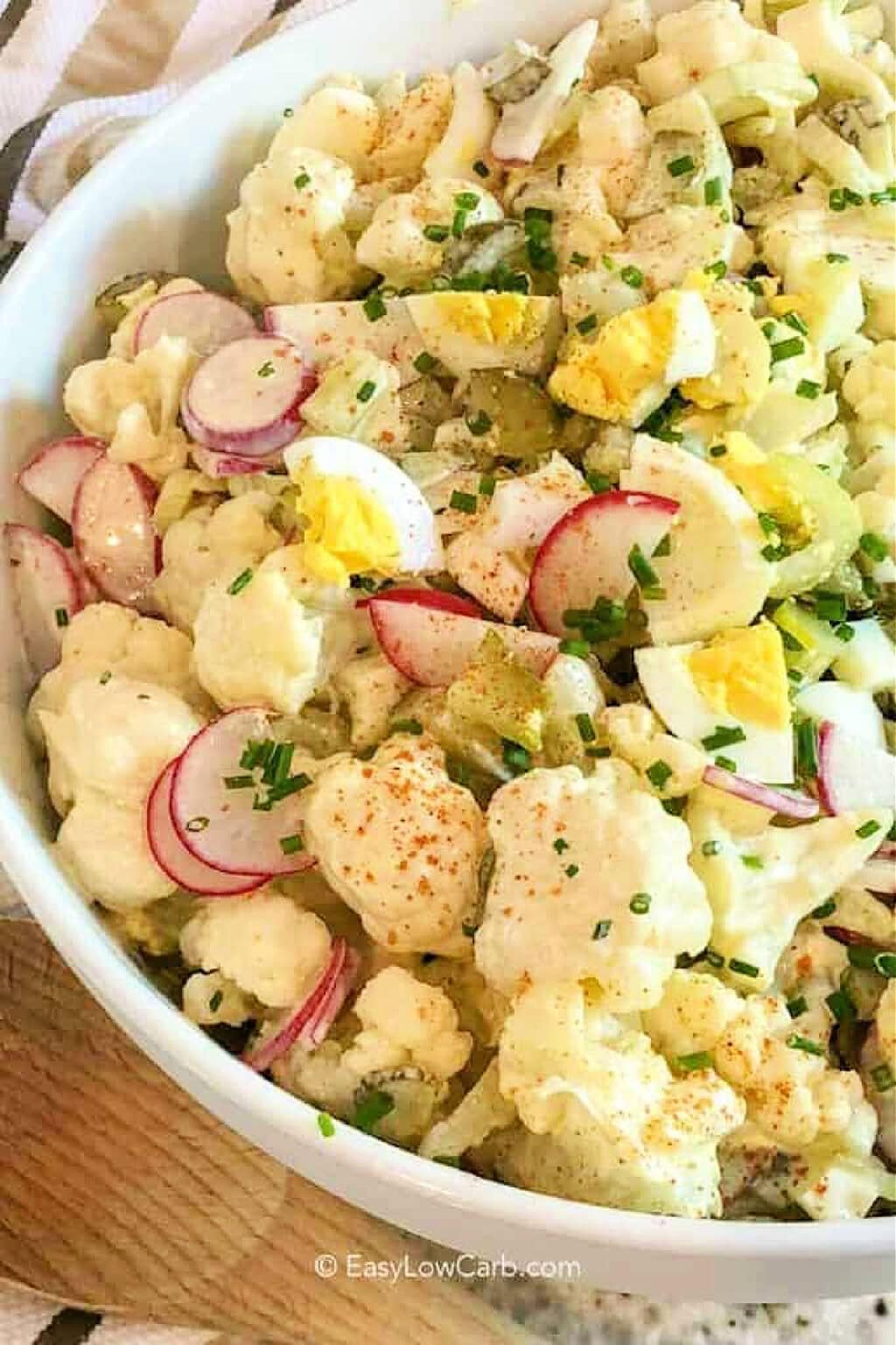Enjoy cauliflower potato salad as a delicious low carb version of the picnic favorite you already love. Creamy dressing, crunchy celery, pickles, radishes, green onions, and eggs turn simple ingredients into a flavorful side that fits almost any menu. This keto potato salad is perfect for sharing with family and friends or keeping on hand for easy lunches. Make a bowl and see why it is sure to become a favorite. #easylowcarb plated Cauliflower Potato Salad