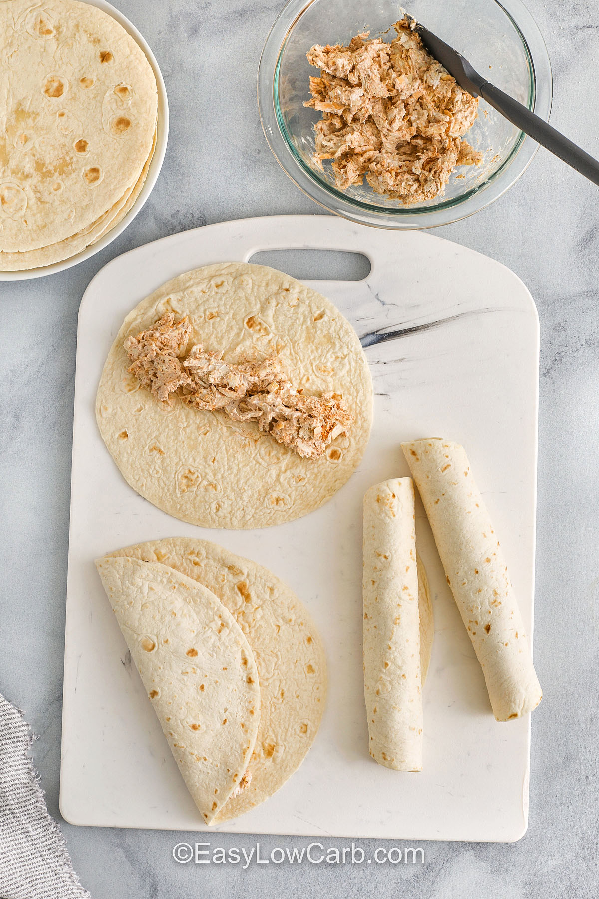 adding chicken to tortillas to make Creamy Chicken Enchiladas