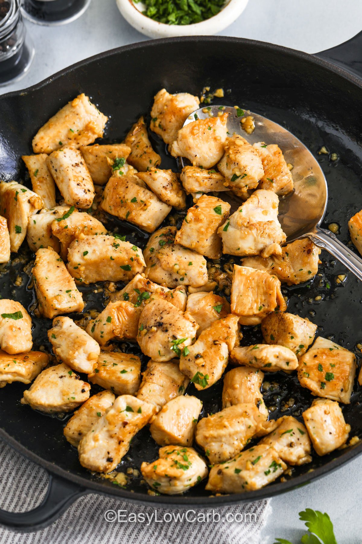 taking a spoonfull of Garlic Butter Chicken Bites out of the pan