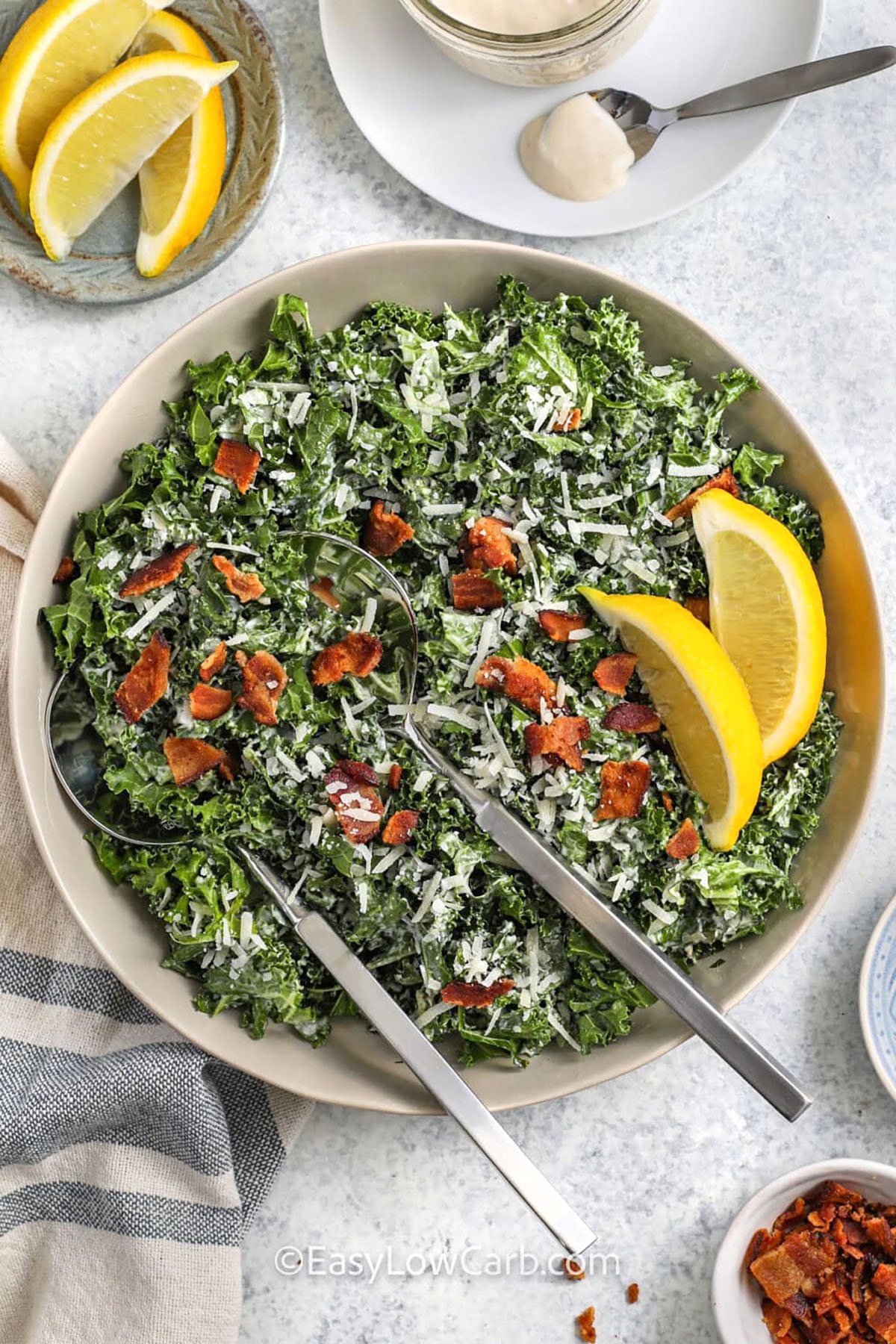 This kale Caesar salad is everything you love about Caesar salad but with a nutritious, hearty base of fresh kale. Massaging the kale softens it and makes it so flavorful. It’s tossed with a rich, creamy Caesar dressing made from pantry staples like mayo, Dijon, garlic, and lemon. Finished with salty bacon, nutty Parmesan, and a pop of citrus, this salad is ready in minutes and perfect for any meal. It’s always a hit at our table! #easylowcarb Kale Caesar Salad with crispy bacon and lemon