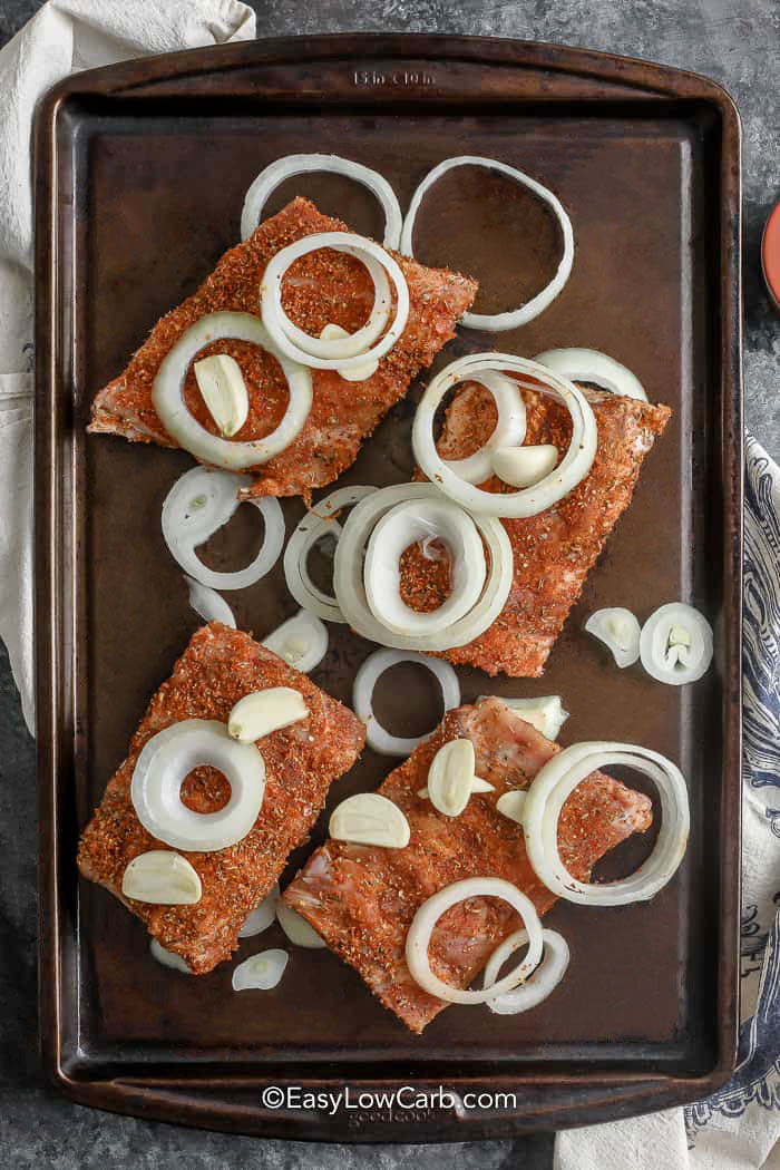adding onions to ribs on sheet pan to make Oven Baked Ribs Recipe