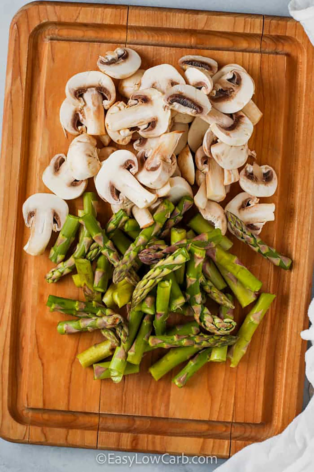 sliced asparagus and mushrooms on a cutting board to make Sauteed Asparagus and Mushrooms