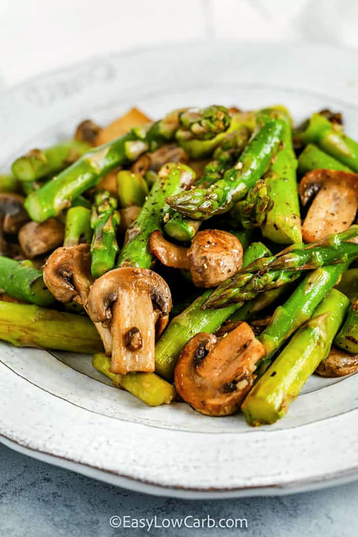 Sautéed asparagus and mushrooms is a quick and flavorful side dish that’s perfect for any low-carb meal. Fresh asparagus cooks up tender-crisp, while sliced mushrooms add savory depth and hearty texture. Finished with butter, garlic, and a splash of liquid aminos, this one-skillet recipe brings bold flavor in every bite. It’s easy enough for a weeknight but tasty enough to serve with your favorite main! #easylowcarb plated Sauteed Asparagus and Mushrooms