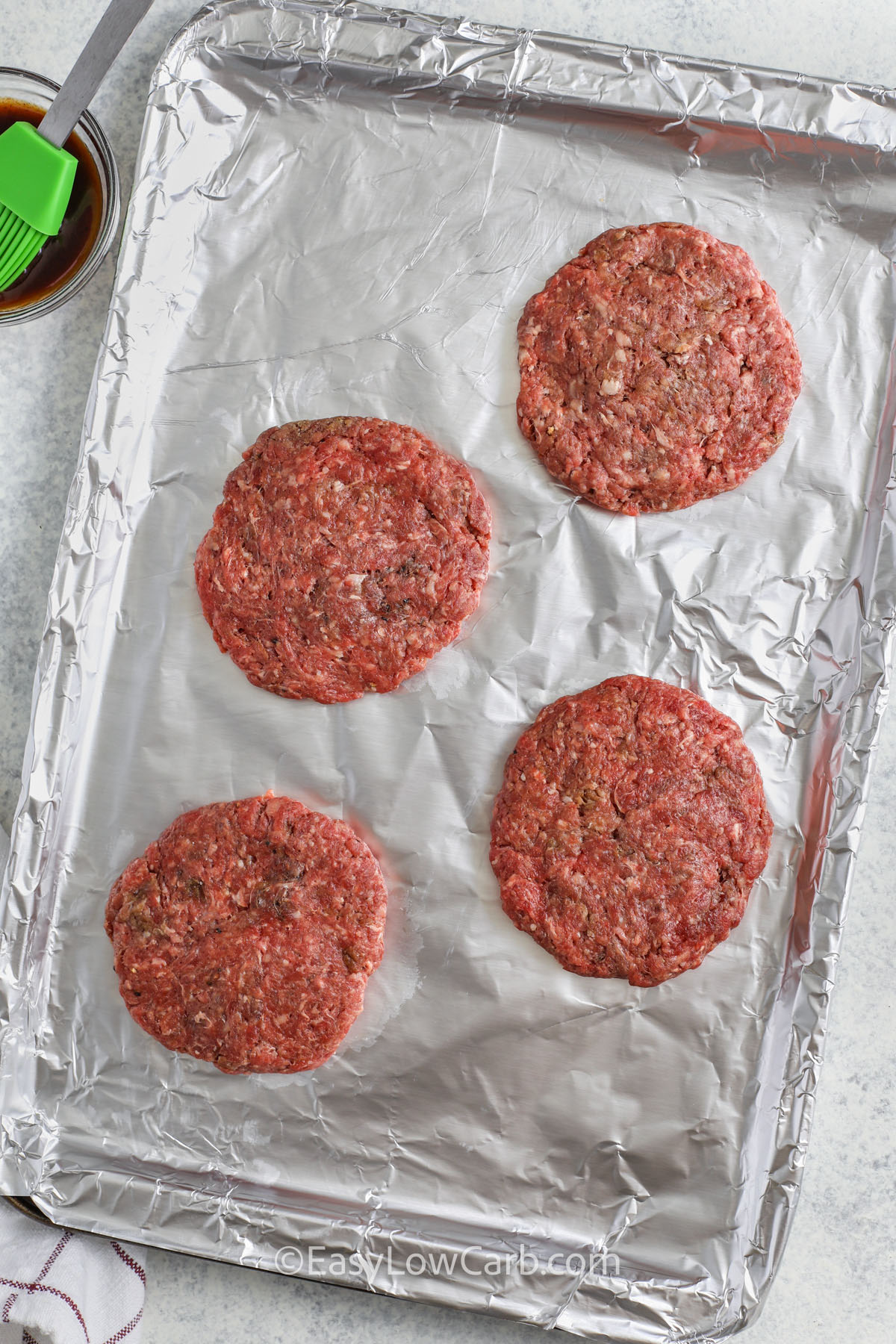 adding hamburger patties to sheet pan to make Cheese Stuffed Burgers