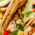 grilled fish tacos topped with cilantro with text