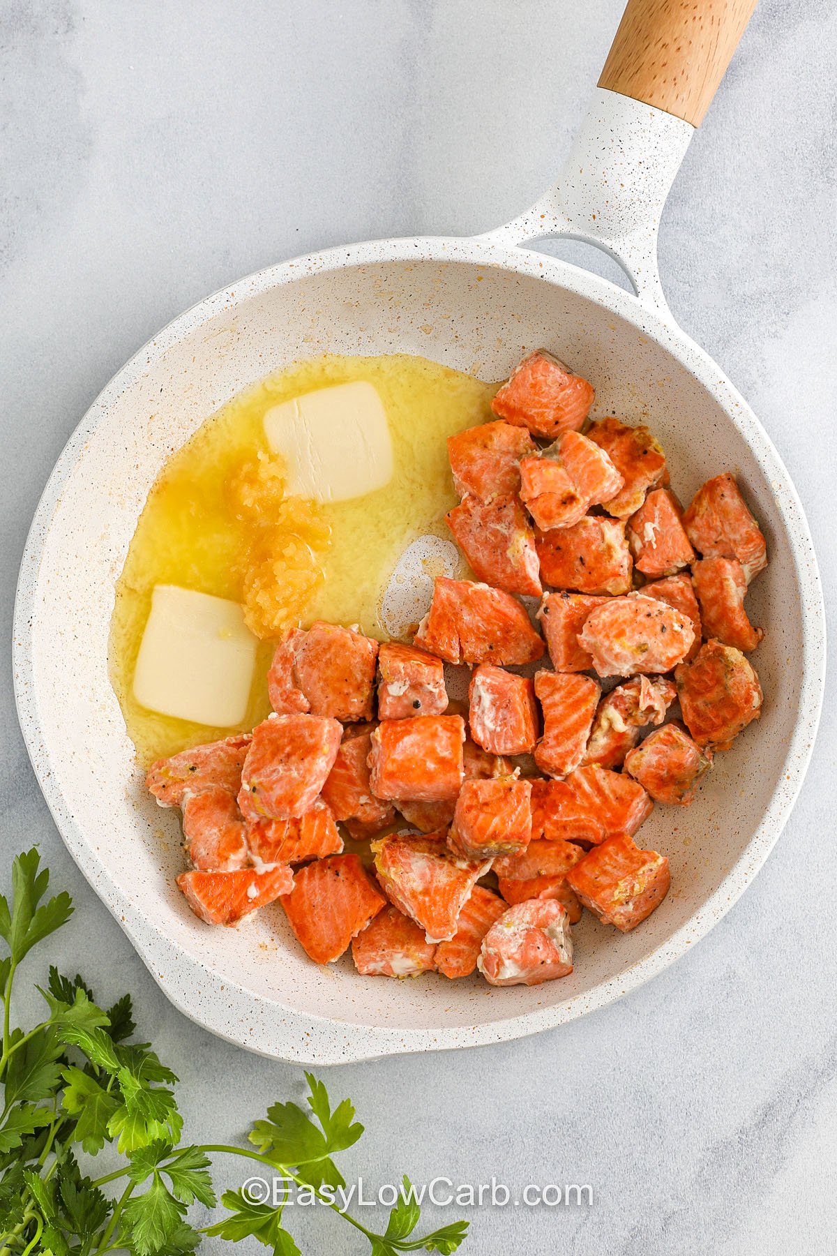 adding butter and garlic to pan with salmon to make Salmon Bites Recipe
