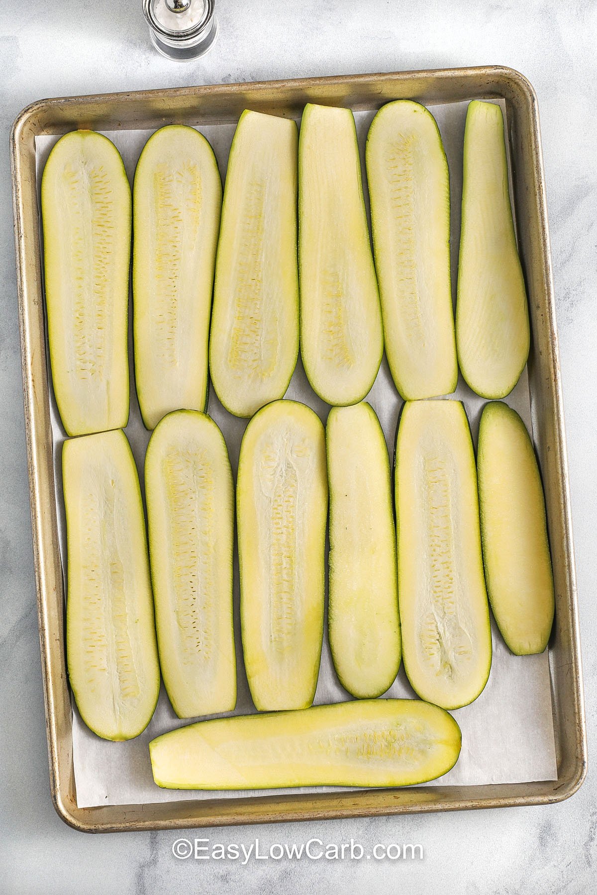 adding zucchini slices to sheet pan to make Zucchini Lasagna recipe.