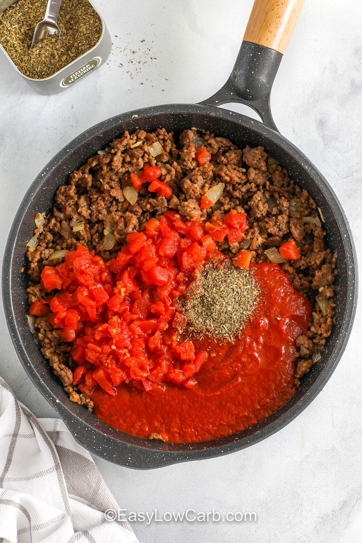 adding ingredintes to cooked meat to make zucchini lasagna recipe