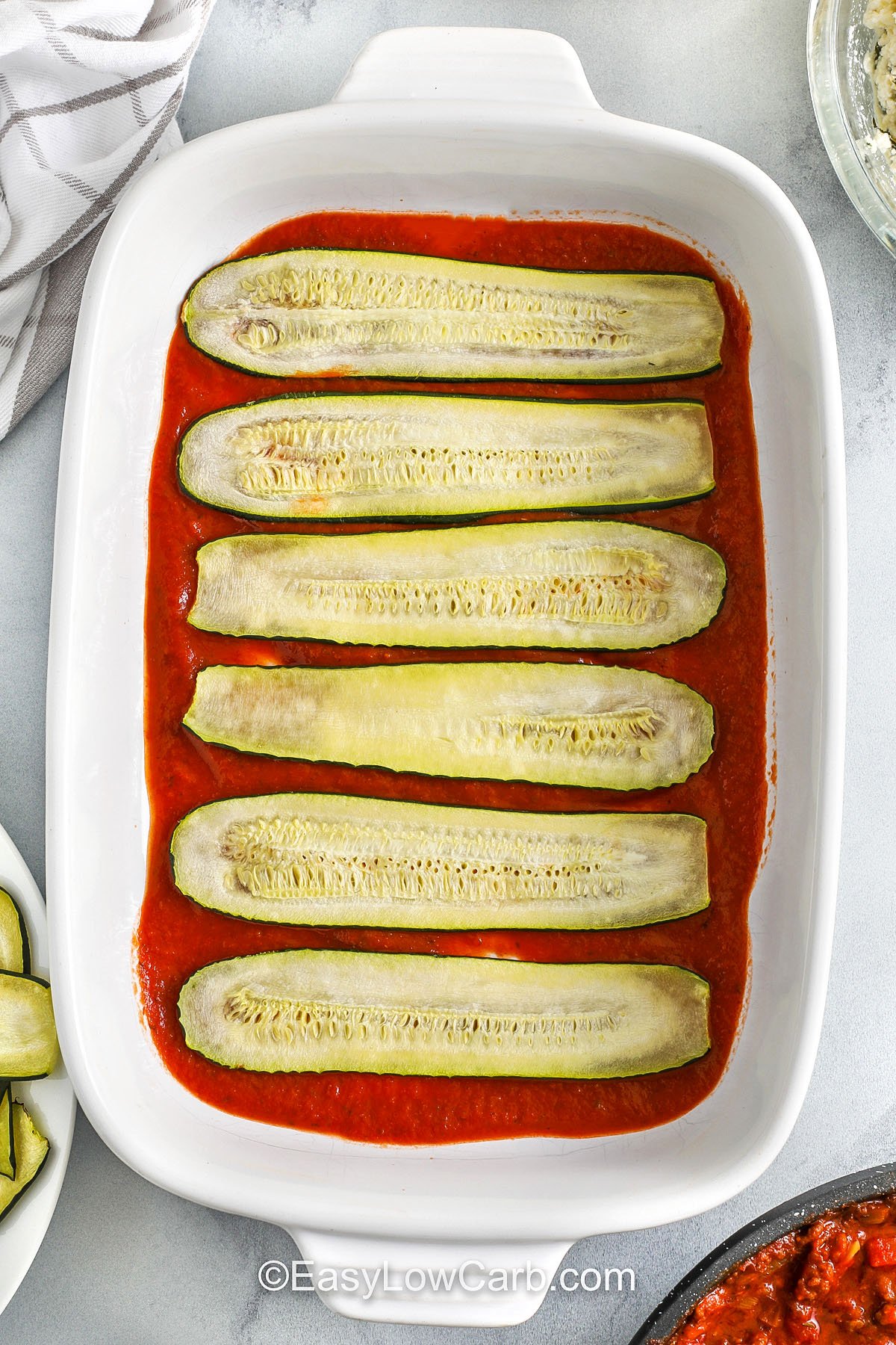 adding layer of zucchini on top of sauce to make zucchini lasagna recipe