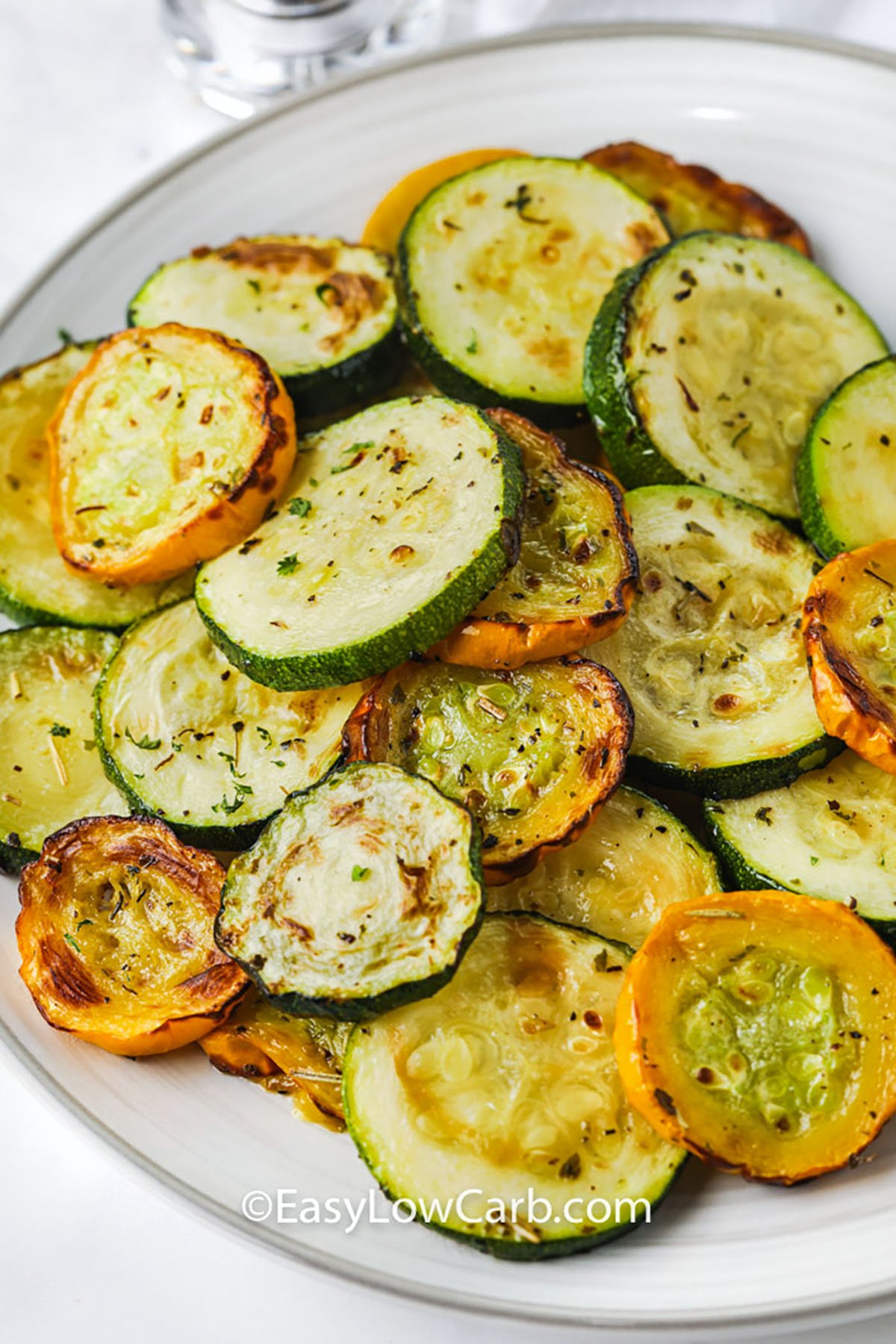 Air Fryer squash is a quick and easy way to make crispy, low carb slices that are full of roasted flavor. A drizzle of oil and a sprinkle of Italian seasoning bring out the best in every yellow squash round. Cooked to tender-crisp perfection, they’re ready in just minutes. Perfect for healthy snacking or a light side. #easylowcarb air fried Air Fryer Squash on a plate