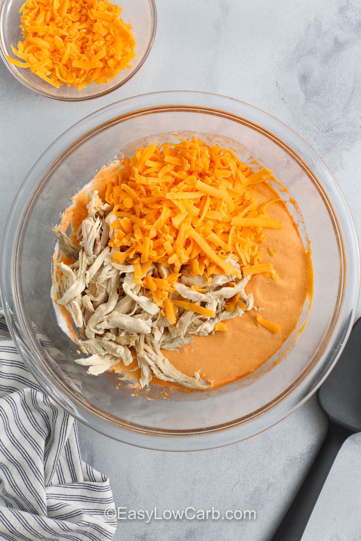adding cheese and chicken to Cottage Cheese Buffalo Chicken Dip mixture to make Cottage Cheese Buffalo Chicken Dip