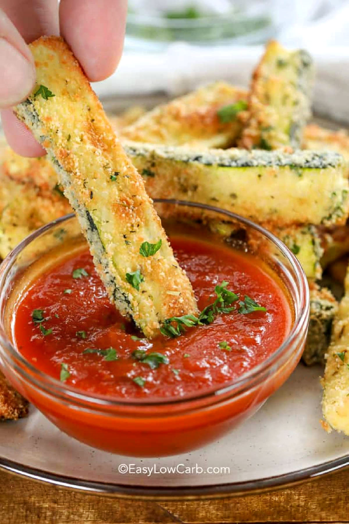 dipping Baked Zucchini Fries in marinara