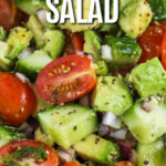 Cucumber tomato avocado salad in a bowl with writing