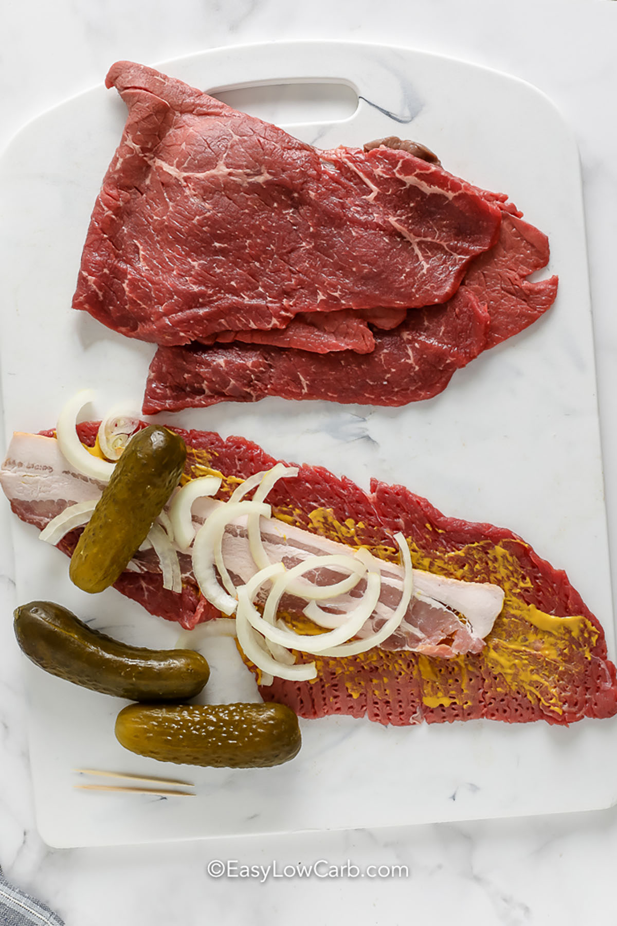 adding pickles , onion , bacon and mustard to beef slices to make Beef Rouladen