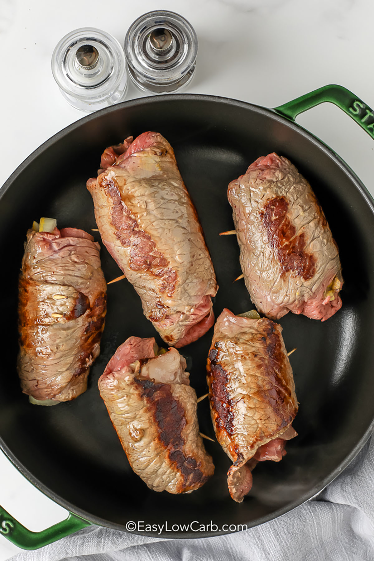 cooking rolled up beef with pickles to make Beef Rouladen