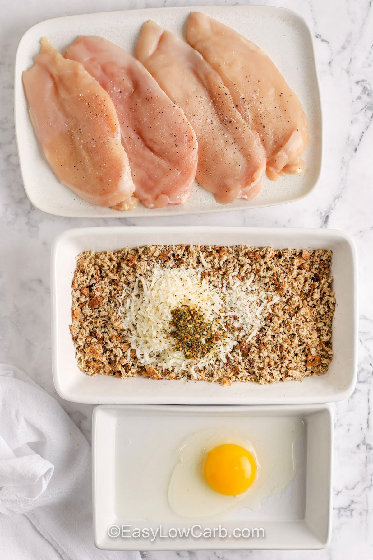 This oven baked chicken Parmesan keeps the classic Italian flavors you love but swaps heavy, fried breading for a keto-friendly coating that’s golden and crisp. Juicy chicken is baked to perfection, topped with savory pasta sauce and melty mozzarella for a rich, cheesy bite every time. Serve it with fresh greens or roasted veggies for a delicious, carb-conscious meal. #easylowcarb ingredients on plates to bread chicken for Oven Baked Chicken Parmesan