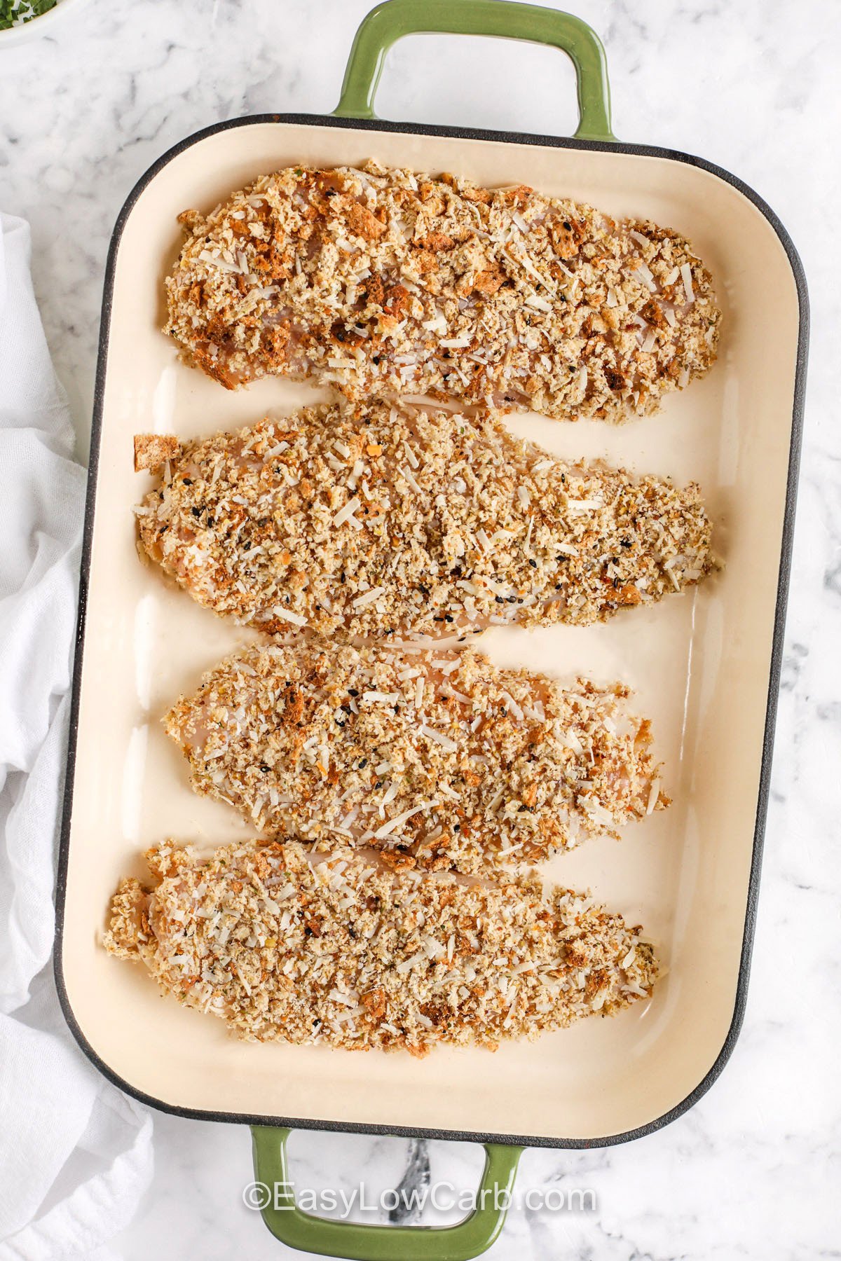 Oven baked chicken Parmesan delivers the rich, cheesy, and saucy flavors you love with a fraction of the carbs. Juicy chicken gets a flavorful crust made from keto bread crumbs and Parmesan, then bakes to perfection before being topped with savory pasta sauce and gooey mozzarella. This guilt-free comfort food makes weeknight dinners both easy and satisfying for the whole family. #easylowcarb adding breaded chicken to dish to make Oven Baked Chicken Parmesan