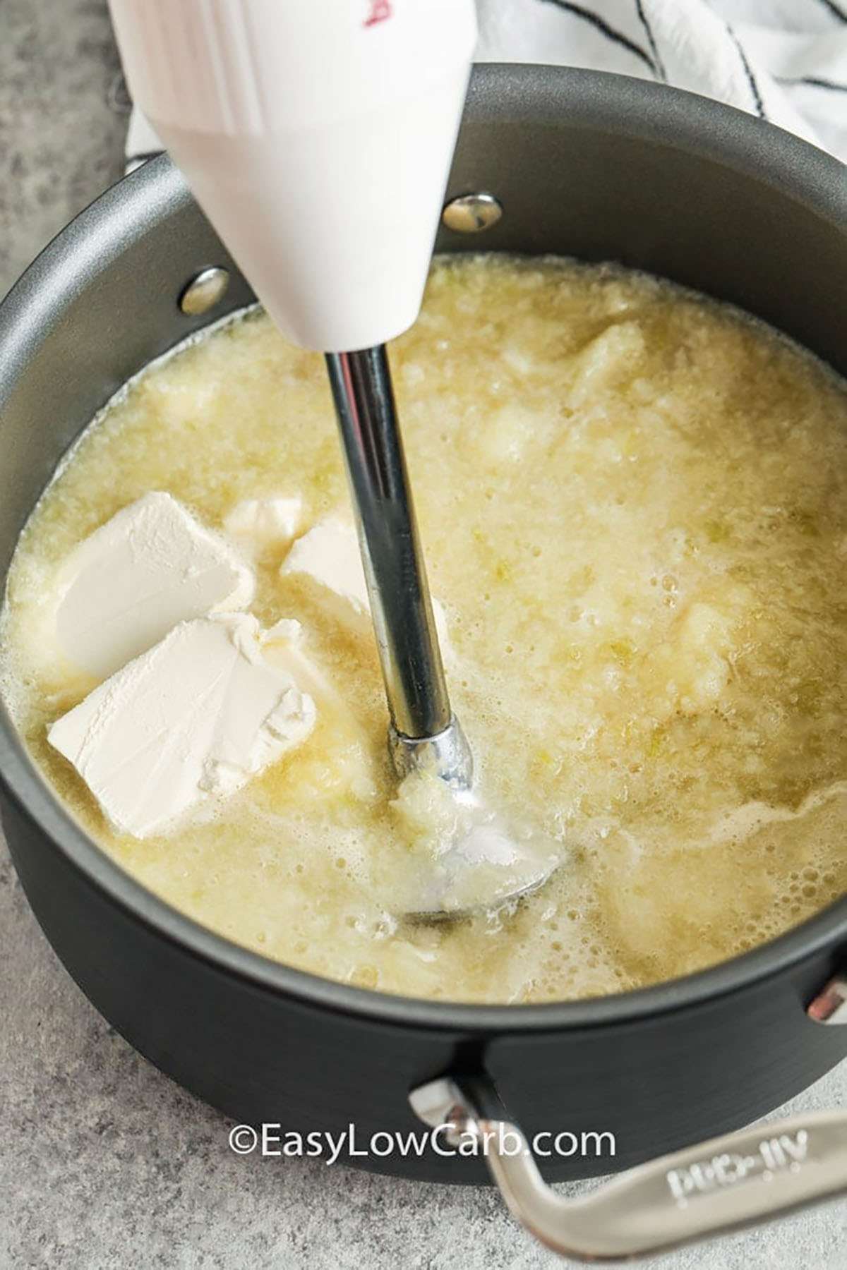 blending cream cheese in ingredients to make Creamy Cauliflower Soup