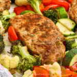 A pork chop cooked on a baking sheet with vegetables