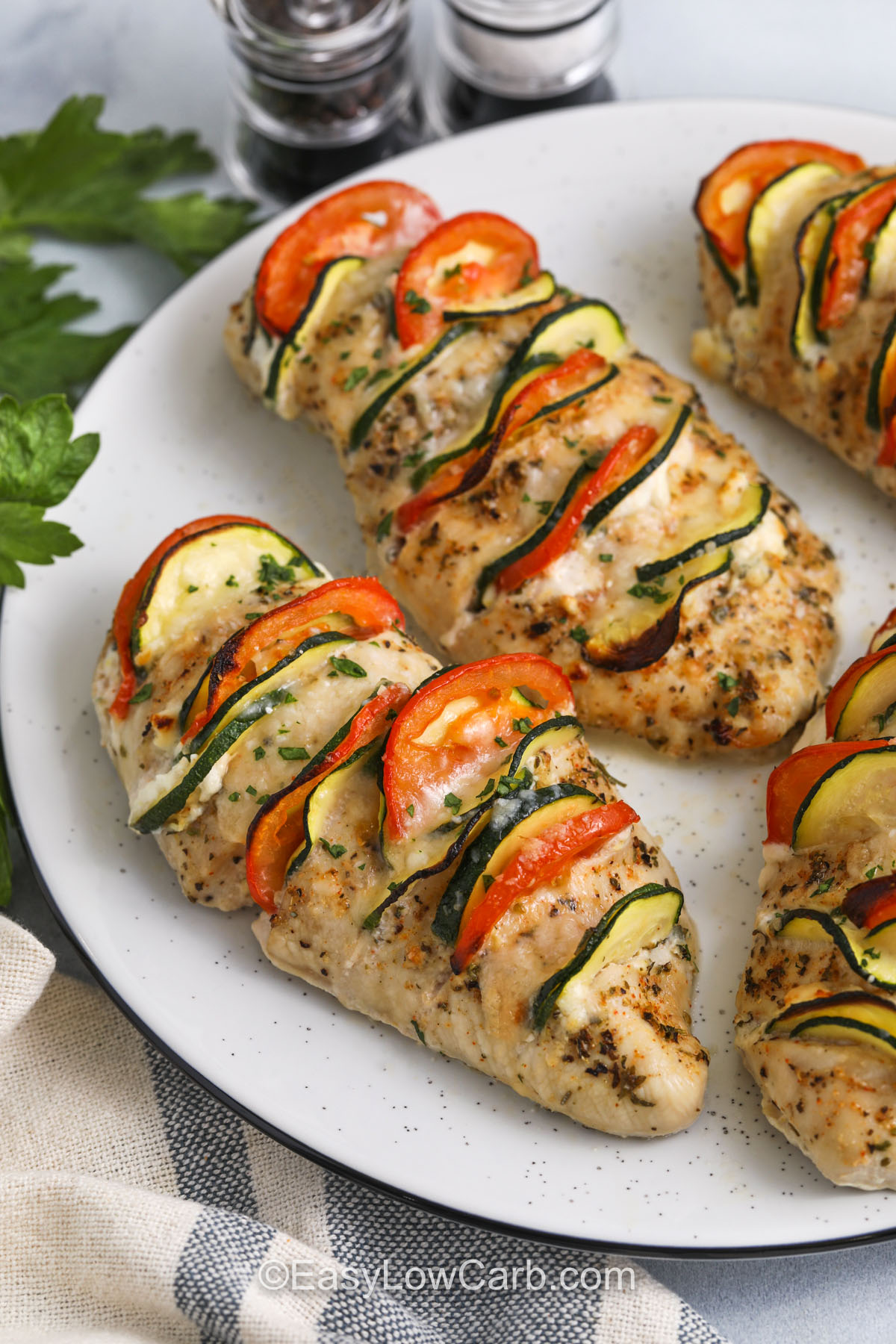 Hasselback chicken features juicy chicken breasts sliced and stuffed with a rich, zesty filling. Cream cheese, lemon zest, and parmesan add a creamy layer, while tomato and zucchini bring color and freshness. It’s a one-pan meal that looks fancy but is surprisingly easy to prepare. Bake until golden and bubbly for a satisfying dinner that fits into your low-carb lifestyle. #easylowcarb Hasselback chicken on a serving dish