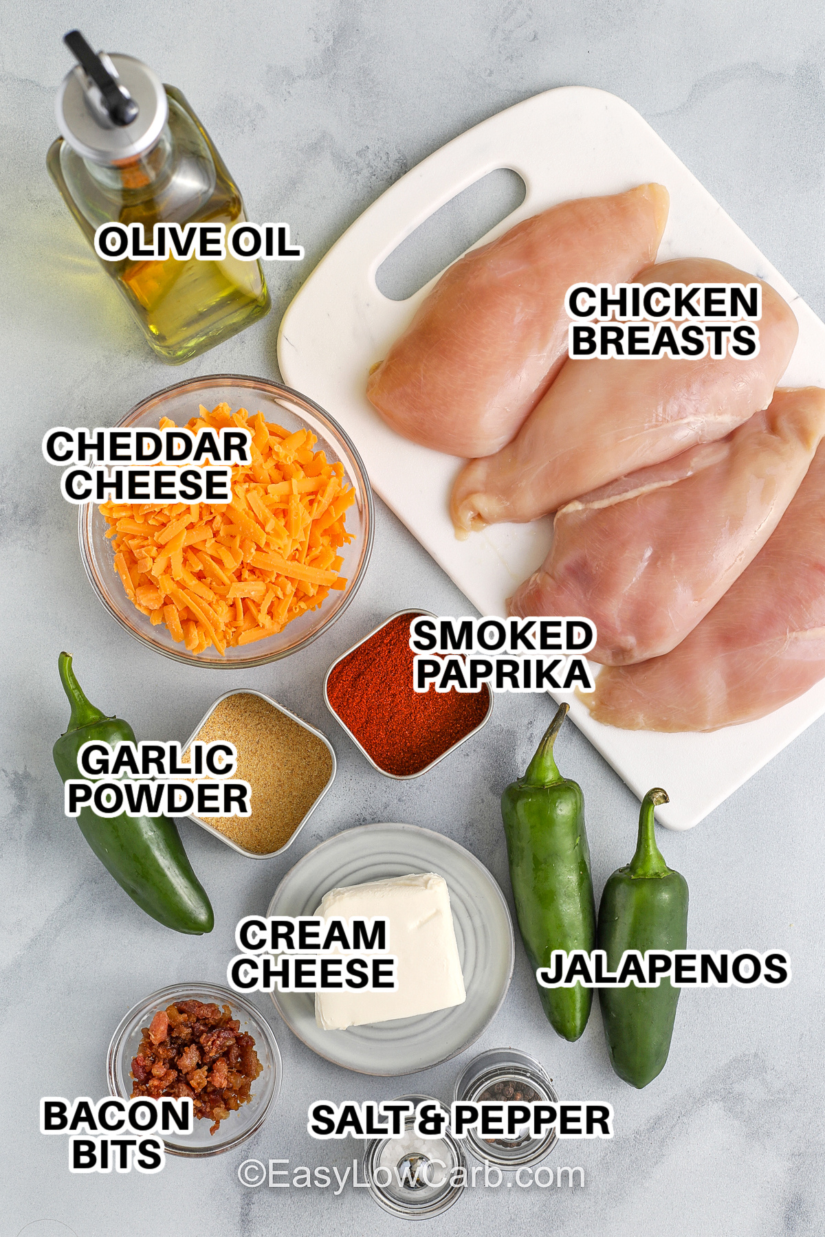 Ingredients to make Jalapeno Popper Chicken, including olive oil, chicken breasts, cheddar cheese, smoked paprika, garlic powder, cream cheese, jalapenos, bacon bits, salt & pepper, with labels