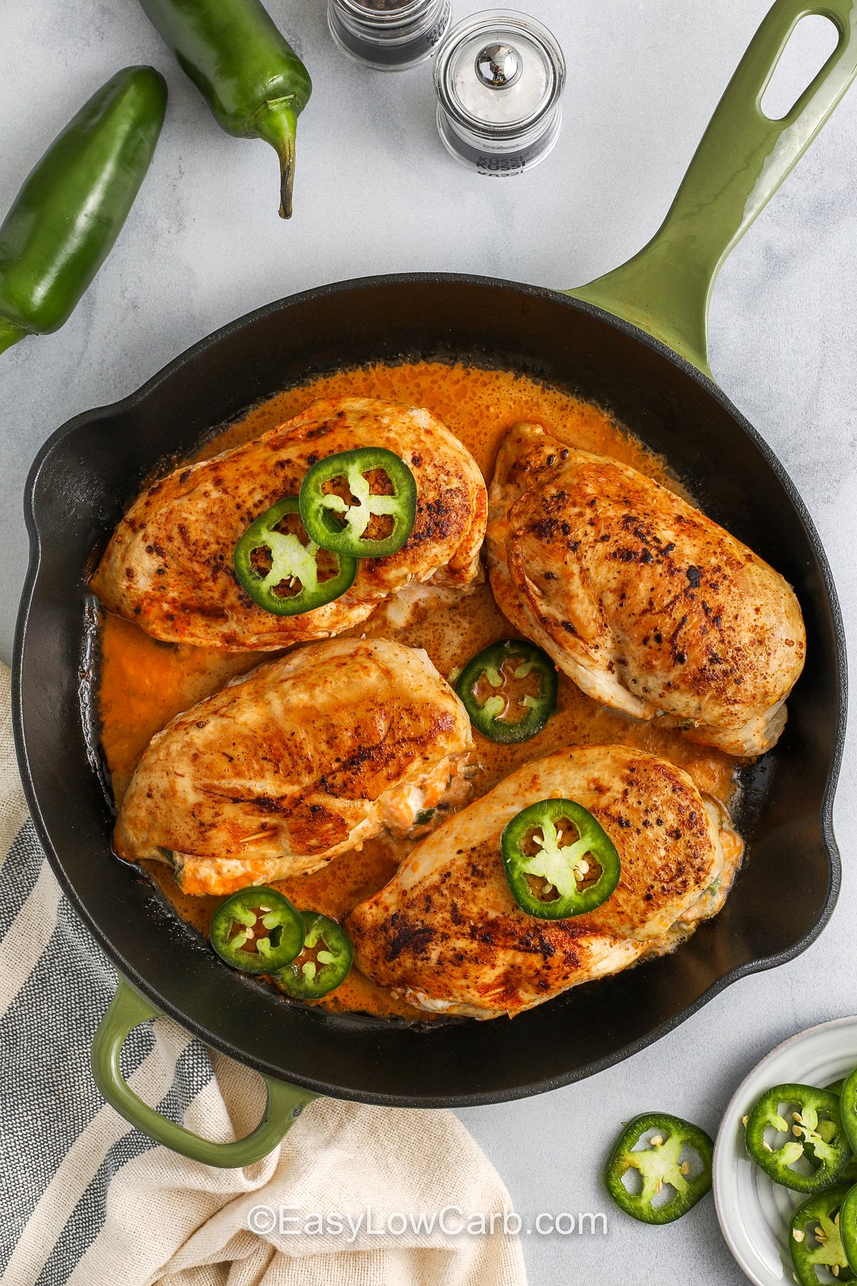 jalapeno popper chicken cooking in a frying pan topped with sliced jalapenos