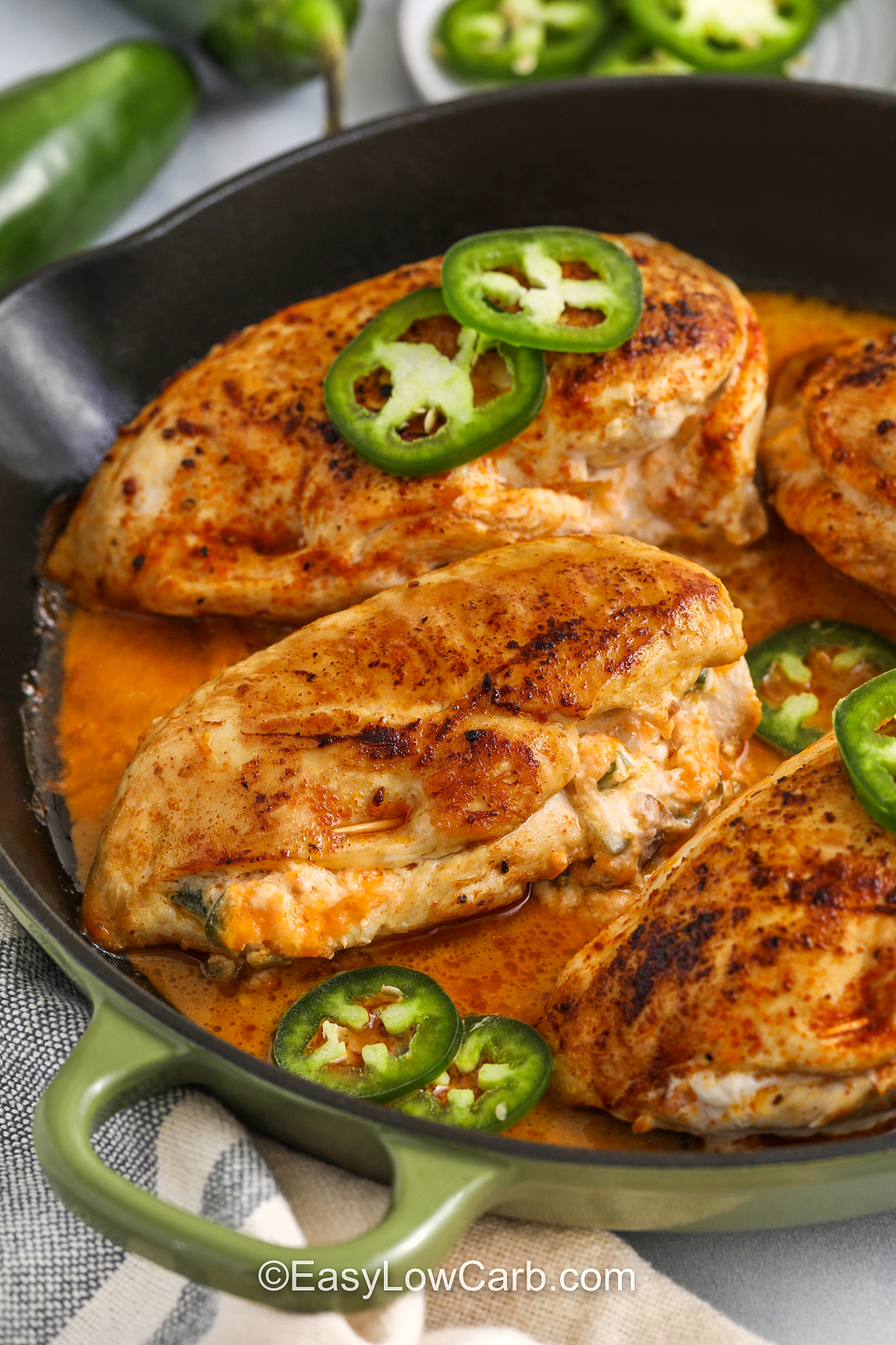 cooked jalapeno popper chicken in a frying pan topped with sliced jalapenos