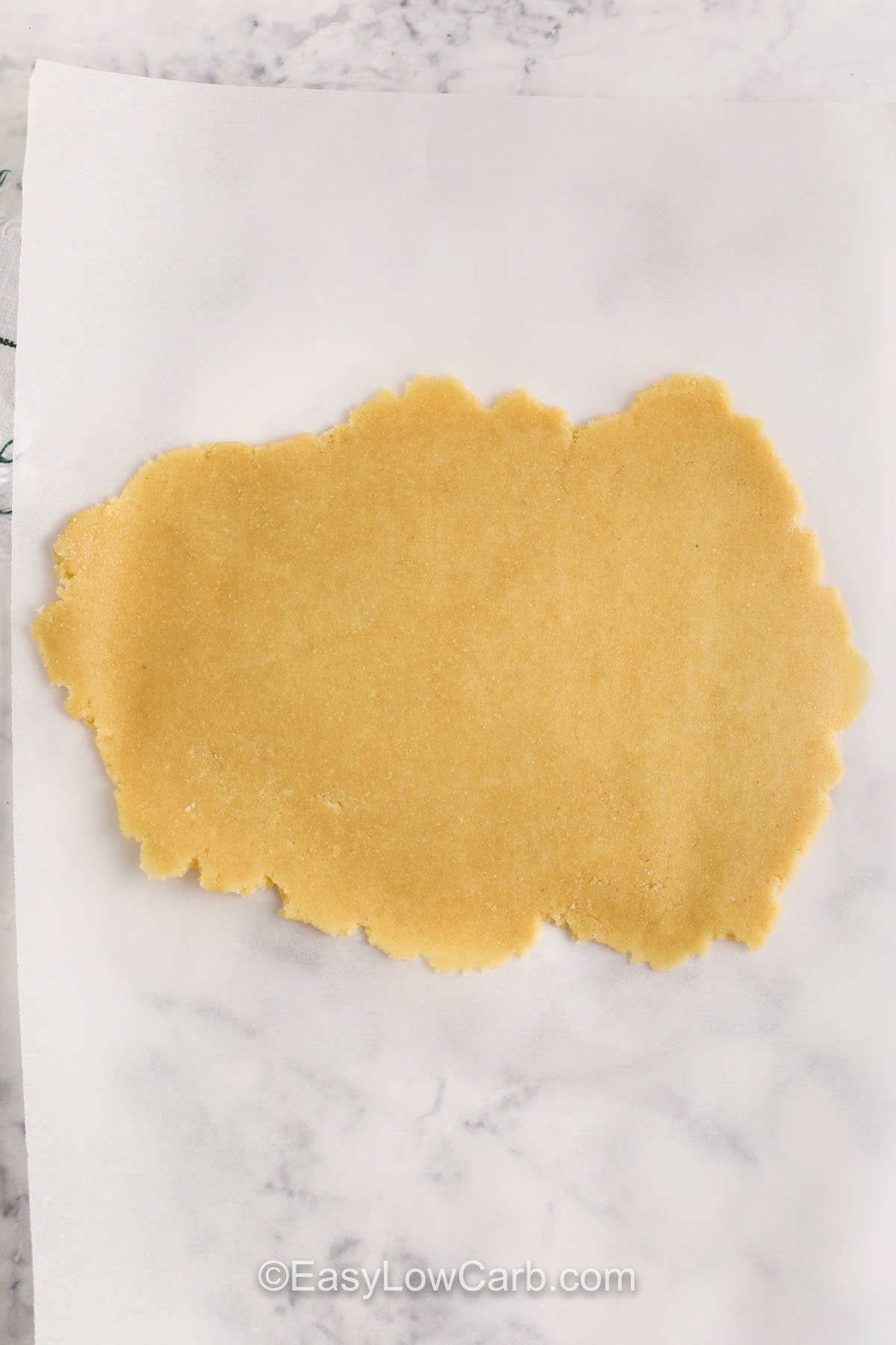 Baked from scratch, this keto crackers recipe gives you the perfect low-carb crunch. With almond flour, egg, and a hint of garlic, these crackers are crisped in the oven and ready in no time. Add herbs or spices to mix things up, or keep it classic. Great for a keto diet or gluten-free lifestyle—simple ingredients, maximum flavor! #easylowcarb keto cracker dough rolled out on parchment paper