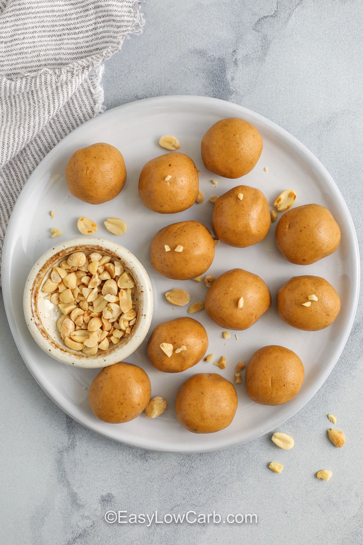 Keto peanut butter balls topped with chopped peanuts on a plate