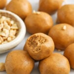 Keto peanut butter balls being served on a plate with a bite missing out of one of them