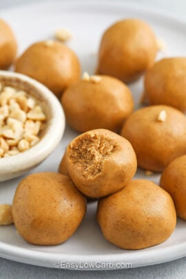 Keto peanut butter balls being served on a plate with a bite missing out of one of them