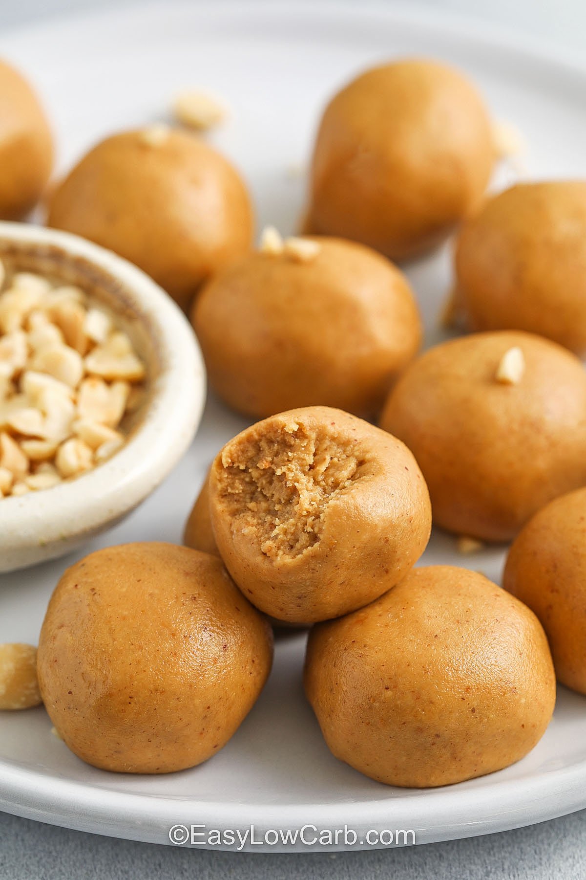 Keto peanut butter balls deliver delicious flavor with wholesome ingredients and no added sugar. The peanut butter base provides healthy fats, while coconut flour gives the perfect consistency without the carbs. These bites are sweetened just right with erythritol and monk fruit, making them an ideal snack for low-carb and diabetic-friendly diets. They come together fast and satisfy sweet cravings in every bite. #easylowcarb Keto peanut butter balls being served on a plate with a bite missing out of one of them