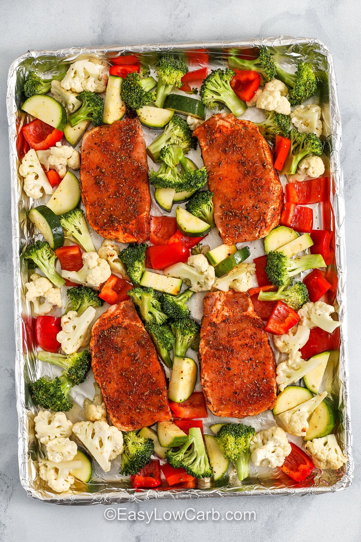 Sheet pan pork chops are a great way to keep dinner simple but impressive. The seasoning blend enhances the meat’s natural flavor while the roasted veggies add color, crunch, and nutrition. No need to juggle multiple pans because everything cooks together evenly. It’s ideal for keto or low-carb lifestyles and pairs perfectly with a side salad or cauliflower mash. #easylowcarb pork chops and vegetables arranged on a baking sheet
