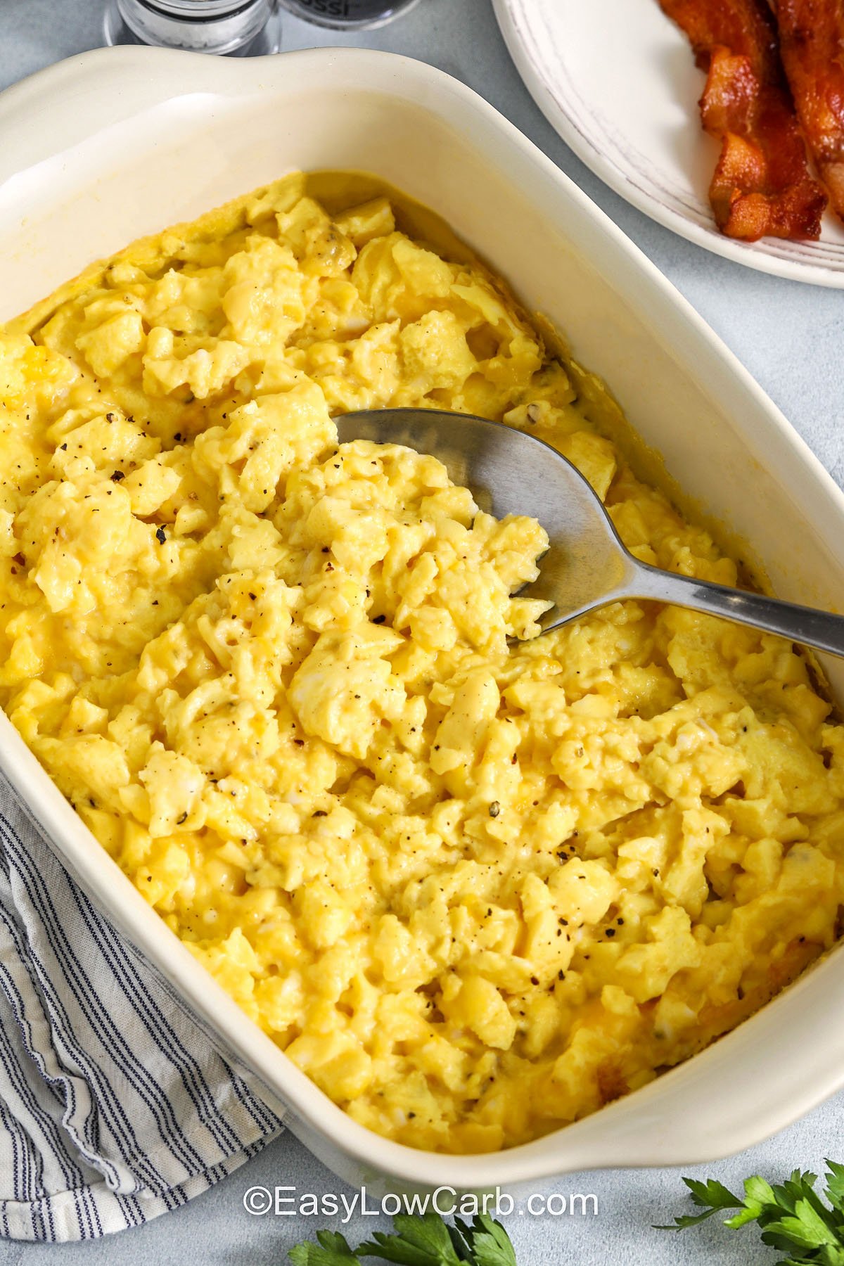 Baked scrambled eggs offer a high-protein, low-carb, and easy recipe that cooks in the oven and is perfect for breakfast or brunch. The sheet pan method helps feed a crowd with very little fuss and gives you room to mix in tasty add-ins like cheese, herbs, or small bits of cooked meat. It is a smart make-ahead option for busy mornings and keeps the kitchen routine running smoothly. #easylowcarb fluffy Baked Scrambled Eggs in a casserole dish