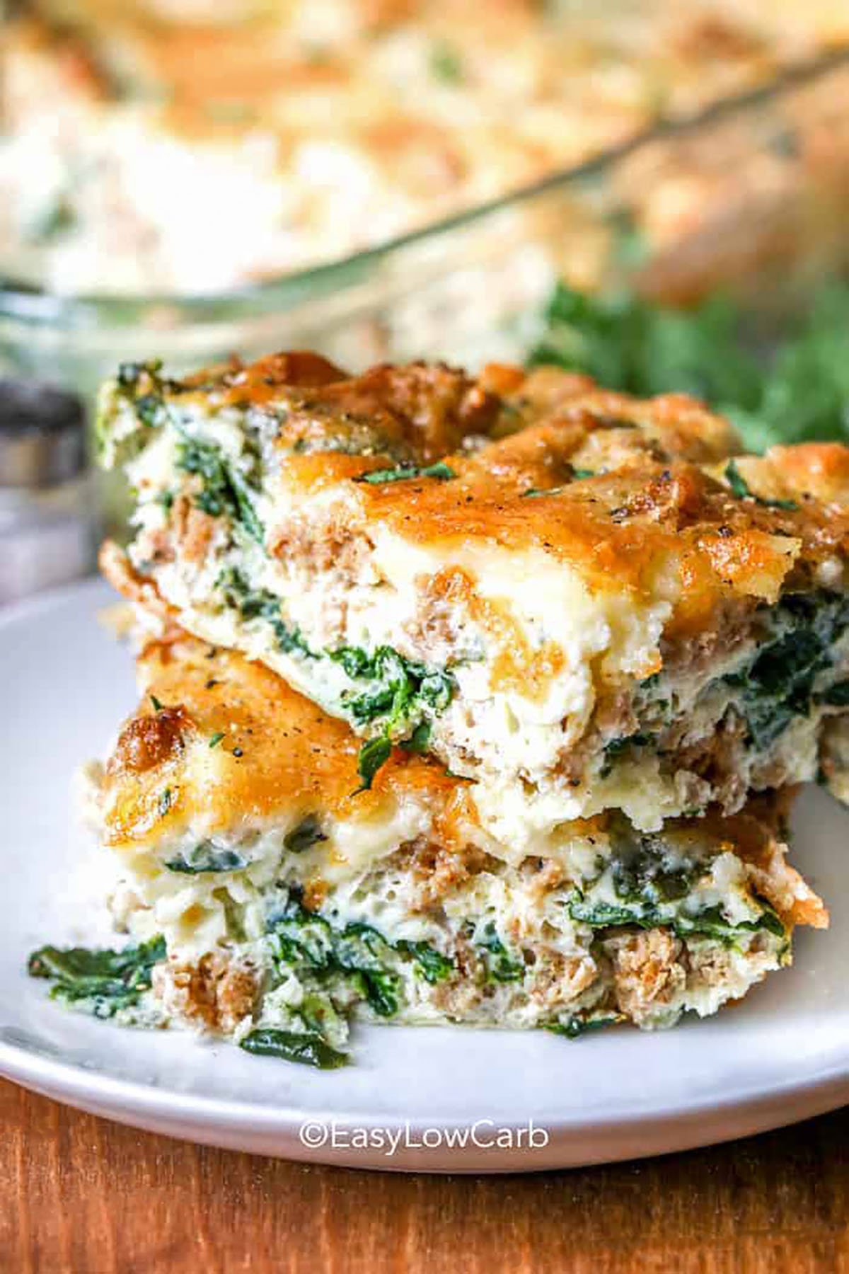 This best breakfast casserole brings together eggs, mushrooms, peppers, spinach, and cheddar for a flavorful morning meal. The cottage cheese keeps the casserole tender while the bacon adds a savory touch. The ingredients mix easily and bake into a golden, fluffy dish that holds well for serving. Great for brunch or weekly prep, it is a reliable recipe full of comforting flavors. #easylowcarb slices of Best Breakfast Casserole on a plate